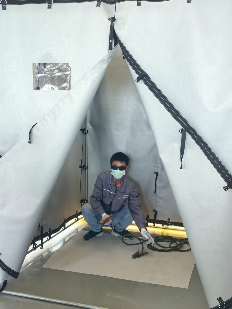 Worker welding inside a welding tent for safe hot work environment