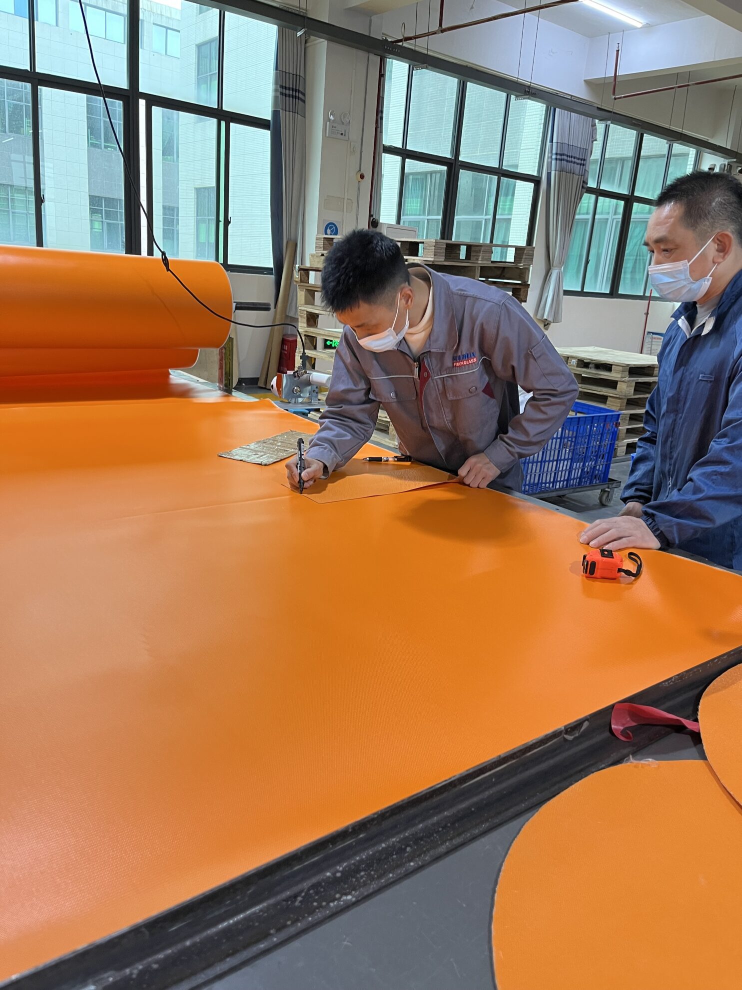 Worker measuring welding enclosure material dimensions for precise installation