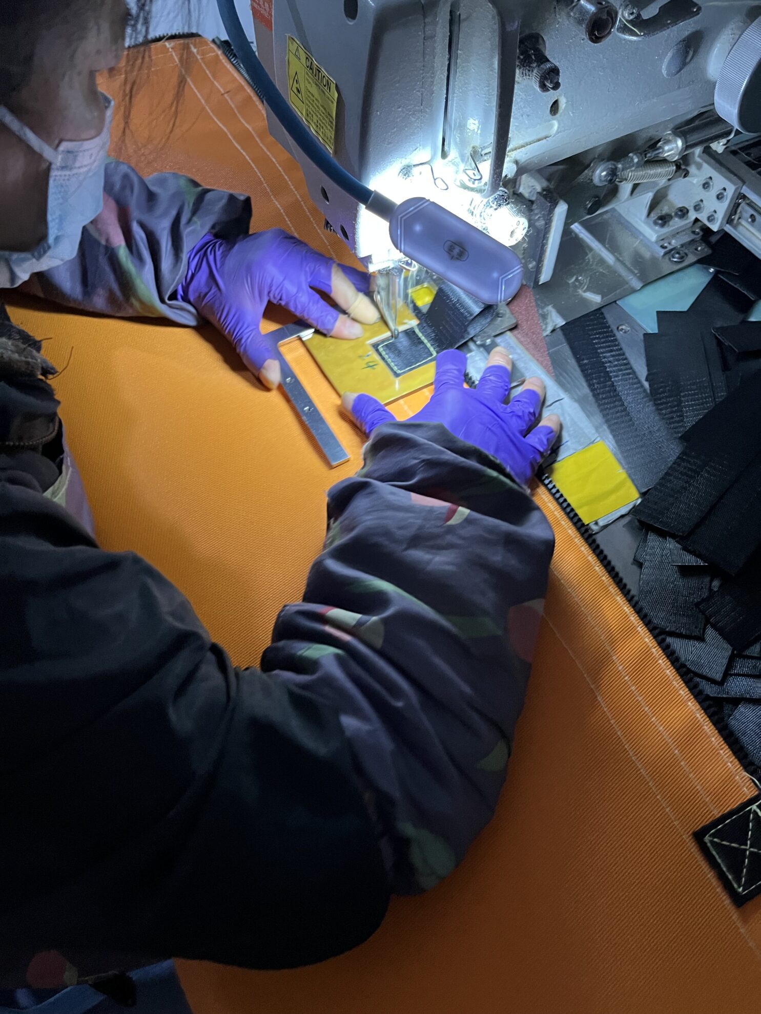 Worker sewing Velcro fasteners on welding enclosure fabric materials