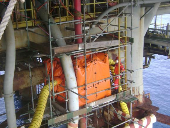 Worker inspecting welding enclosure system installed on offshore platform